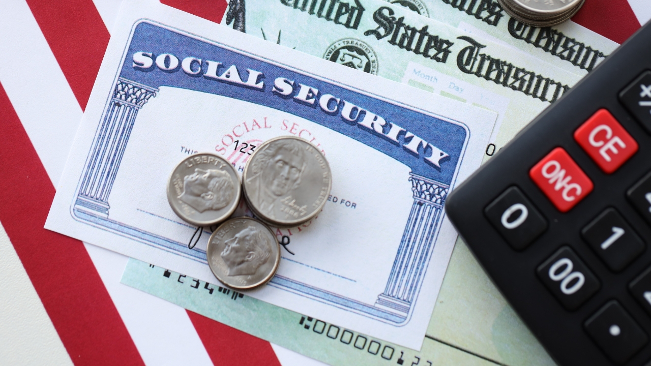 Social Security card with coins, checks, and a calculator on an American flag background