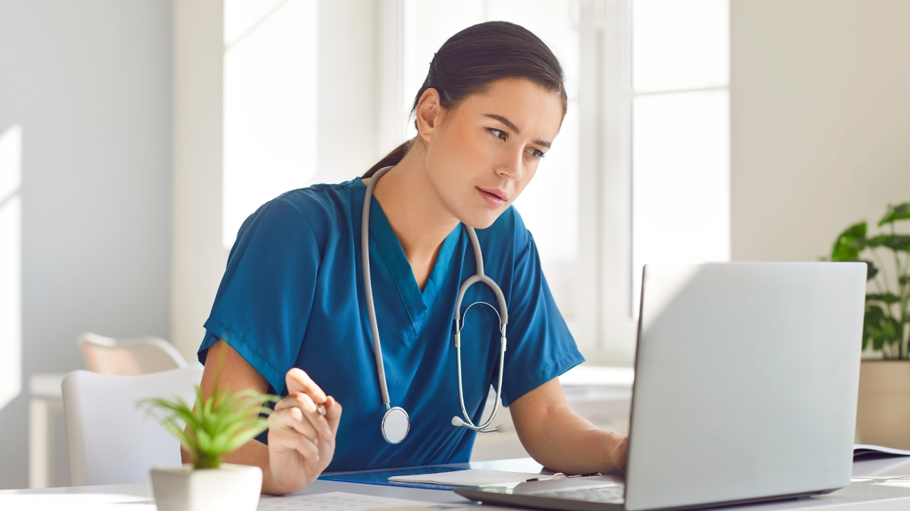 A nurse reviews patient notes on a laptop during a hospital shift