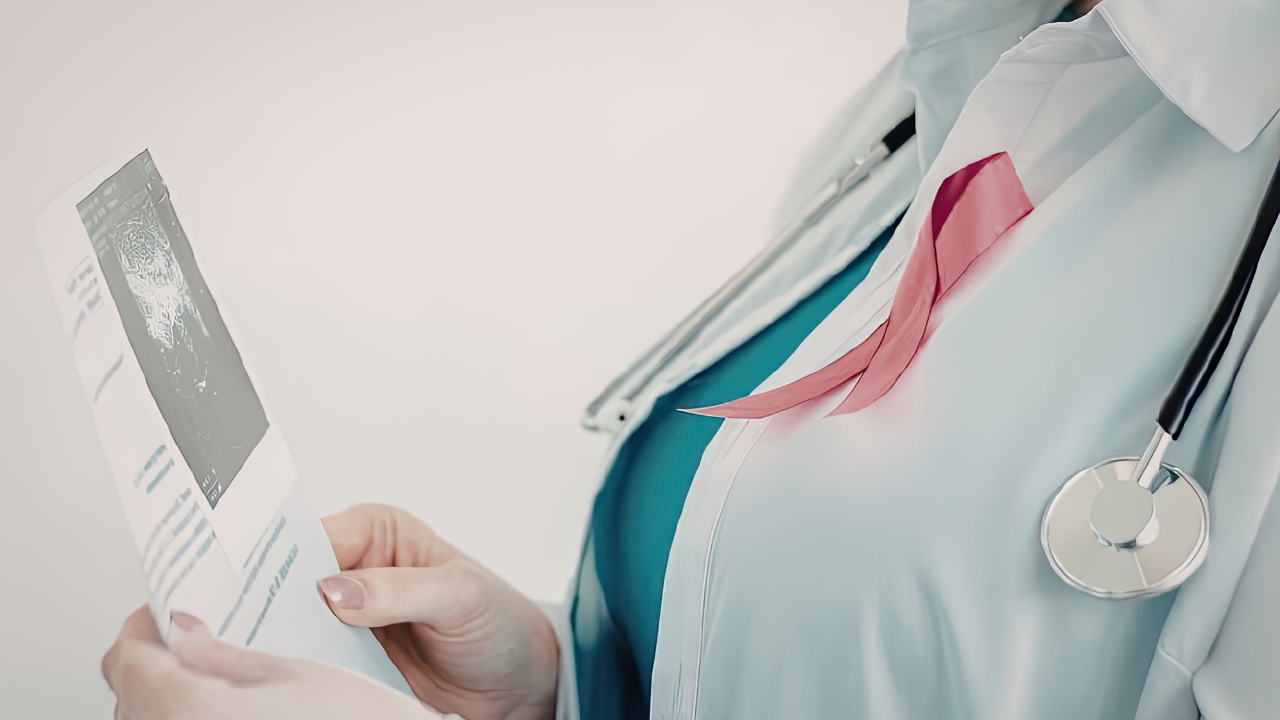 Doctor reviews a breast cancer report with a pink ribbon on her coat