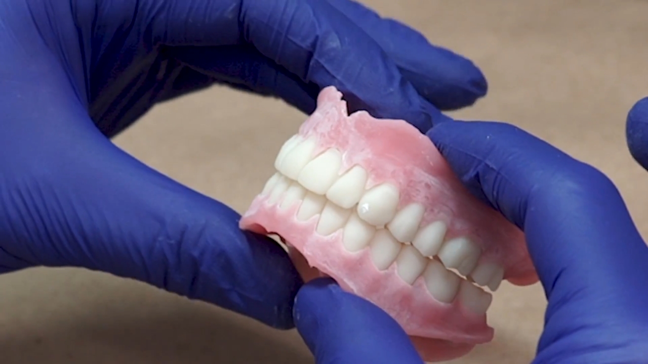 A dental technician checks the fit and finish of a 3D printed denture
