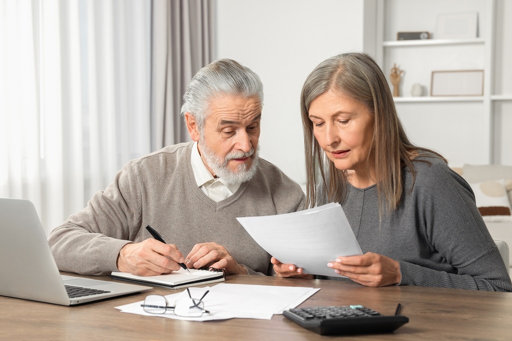 Senior couple reviewing Social Security payment documents and monthly financial paperwork at home