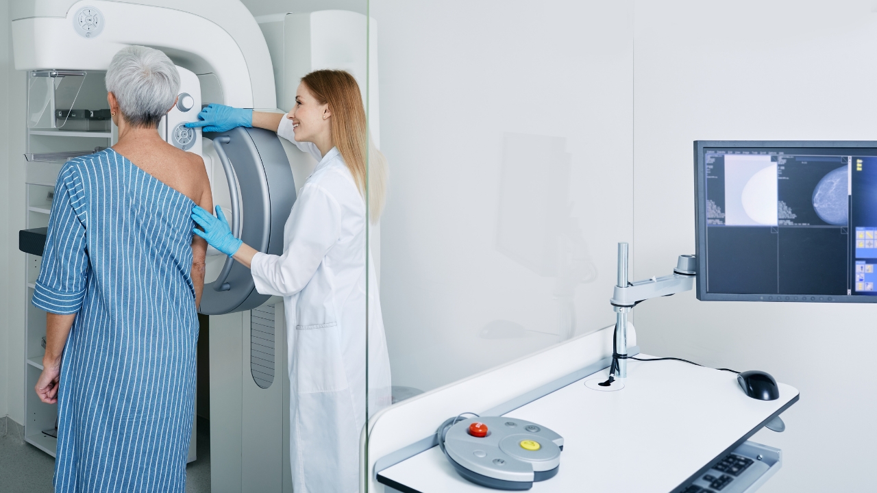 Clinician helps a patient during a mammogram exam in a breast imaging room