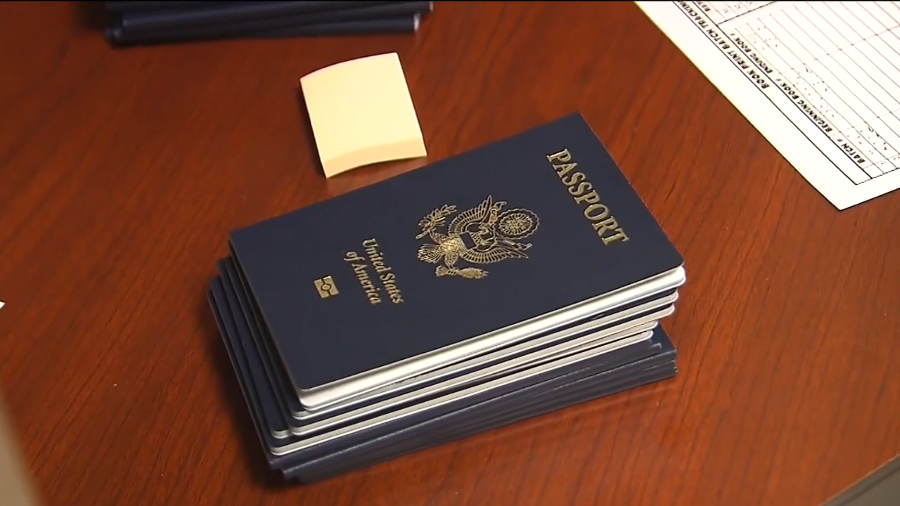 A stack of U.S. passports sits on a wooden desk