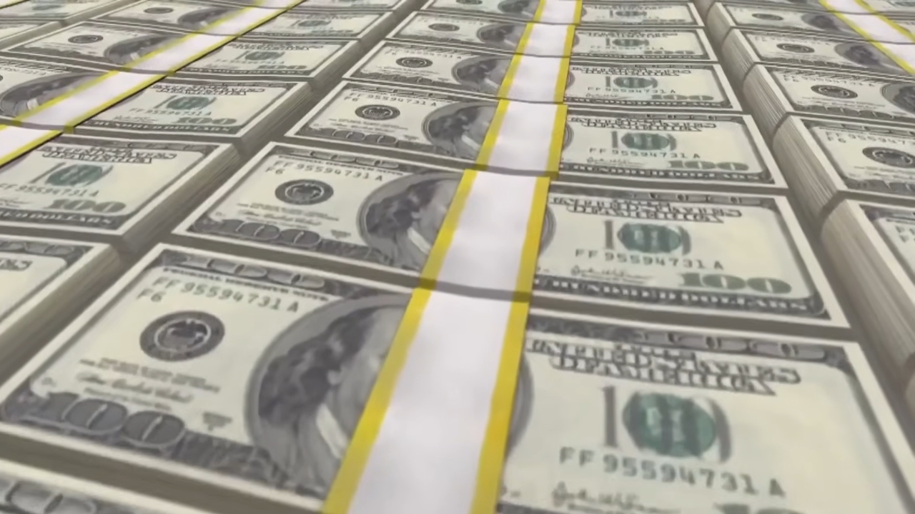 Stacks of $100 bills are lined up in rows with yellow bands
