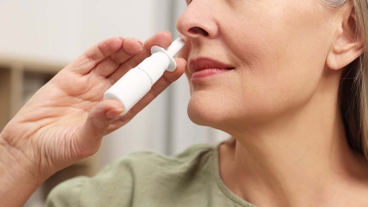 Woman using a nasal spray at home