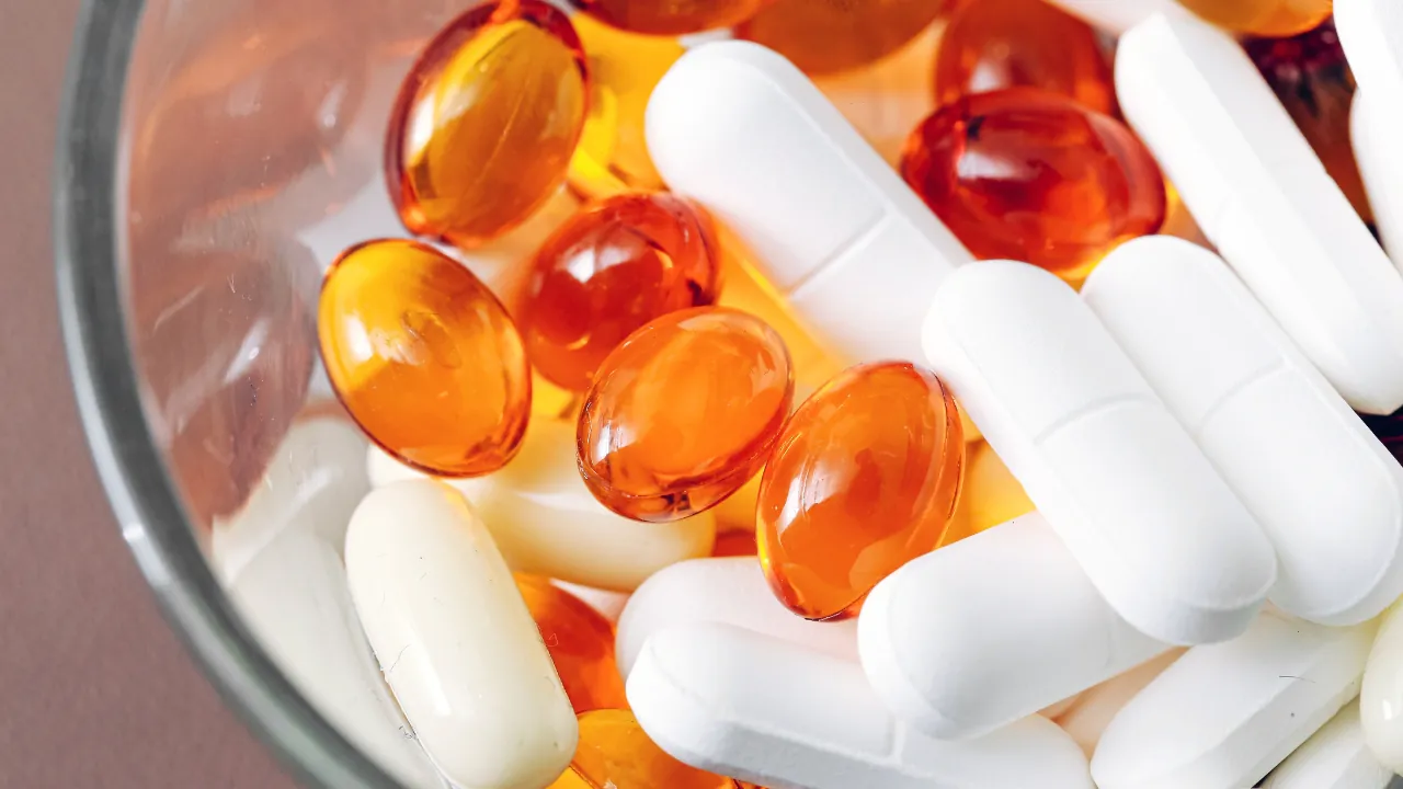 White tablets and orange capsules in a bowl for FDA dietary supplement updates for 2026