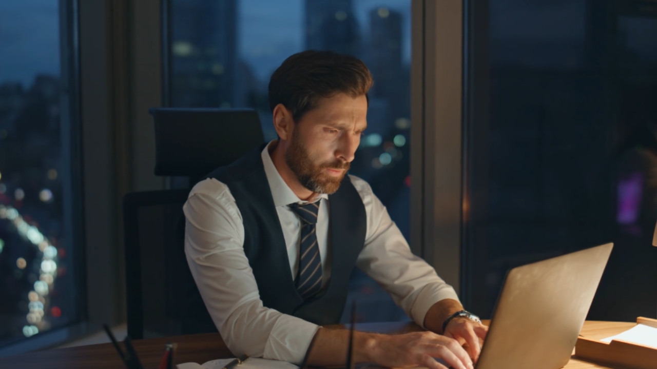 Man works late at a laptop in a dark office