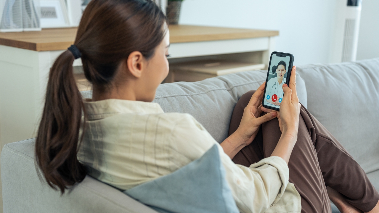Woman speaks with a doctor on a telehealth video call at home