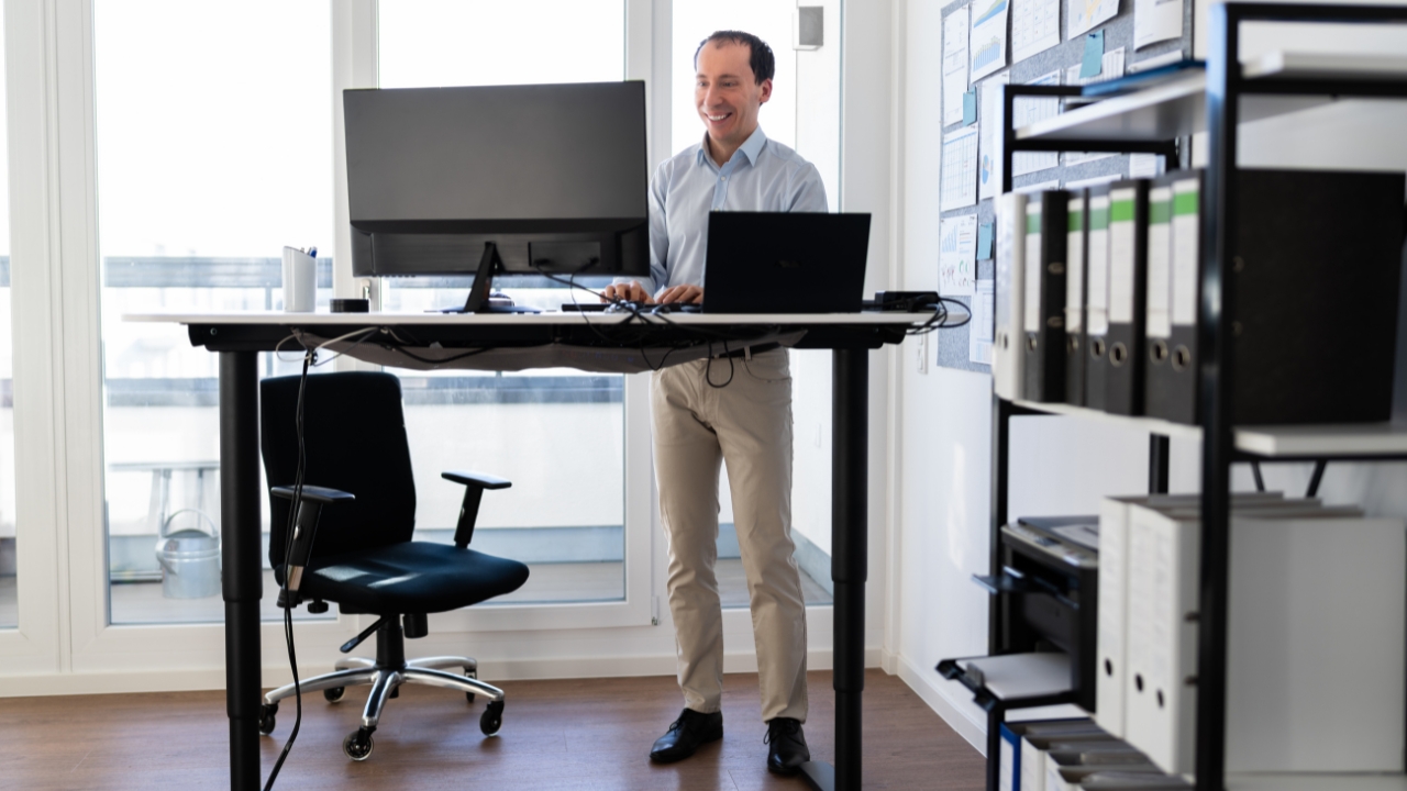 Man uses a sit-stand desk in a bright office