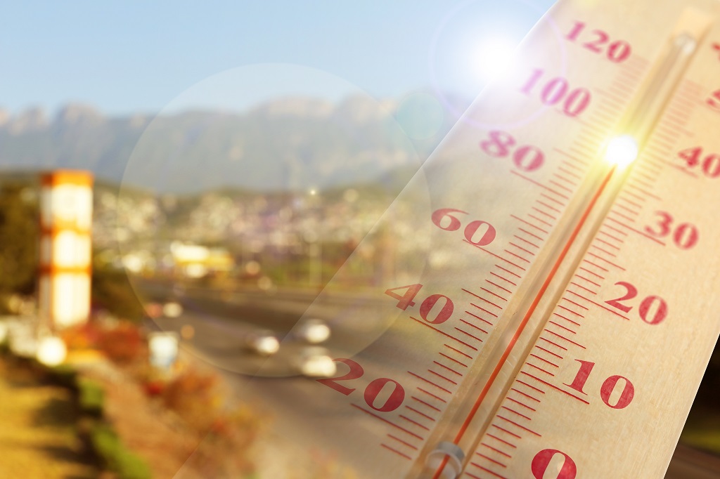 Thermometer showing extreme temperatures during a summer heatwave with a blurred urban landscape in the background