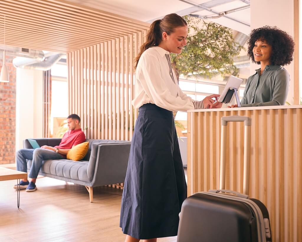 Hotel guest checking in at the reception desk while completing registration for a reserved room