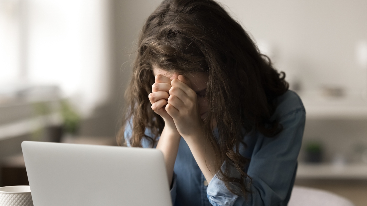 Woman appears overwhelmed at a laptop during a difficult moment