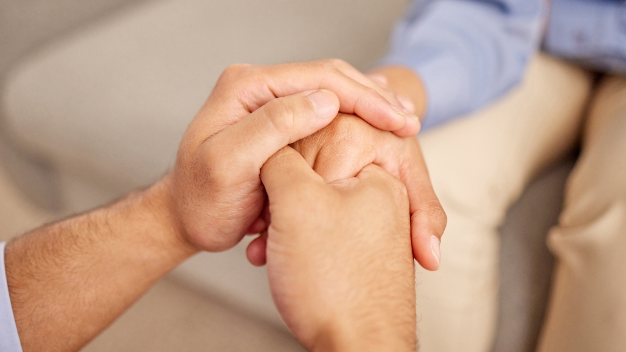 Two people holding hands during a supportive mental health conversation
