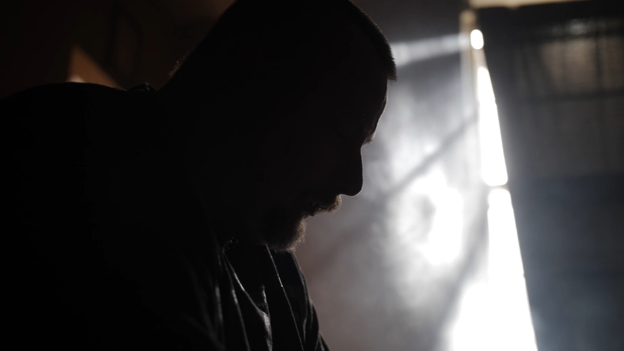 A man sits in shadow near a bright window