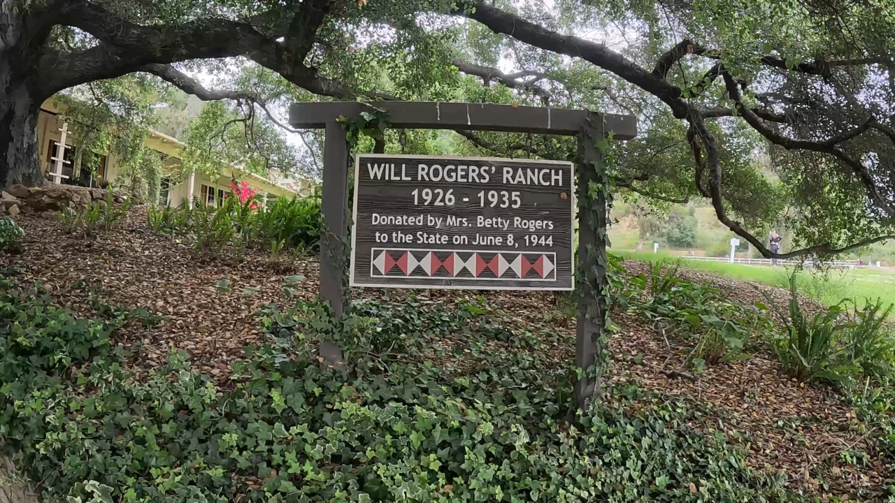 The Will Rogers Ranch sign sits under oak trees at Will Rogers State Historic Park
