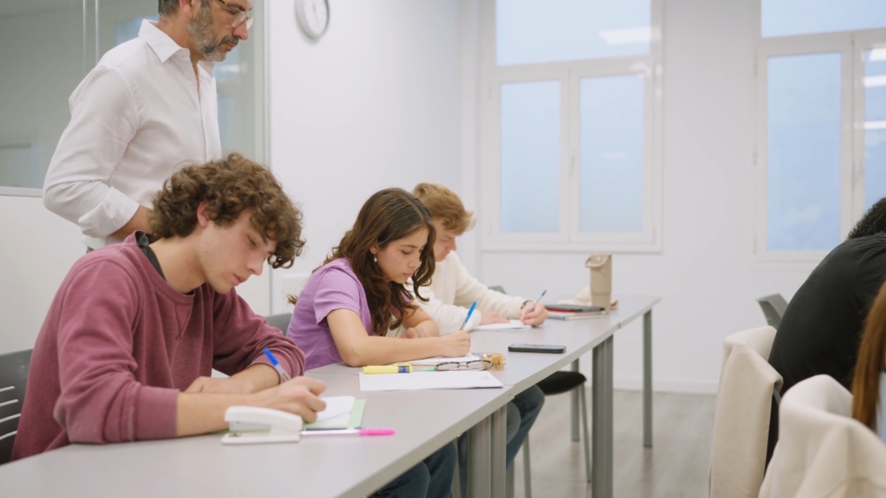 Students complete handwritten exams under a teacher’s supervision