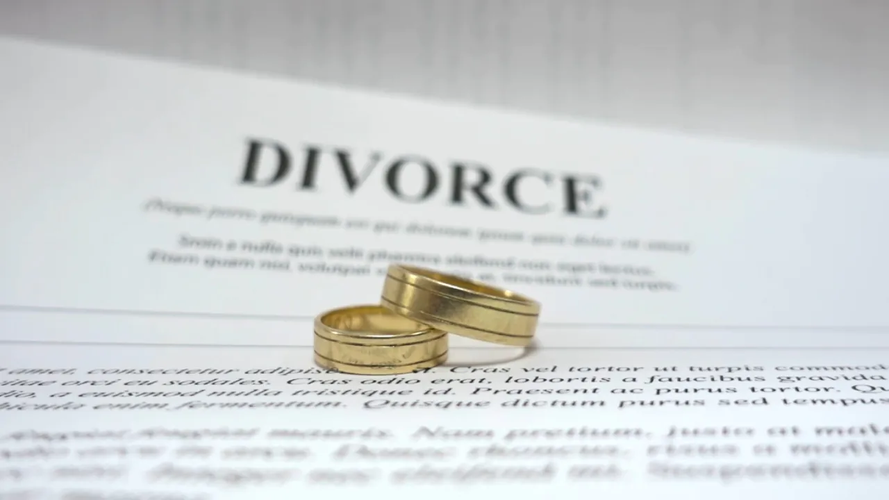 Gold wedding rings rest on divorce papers