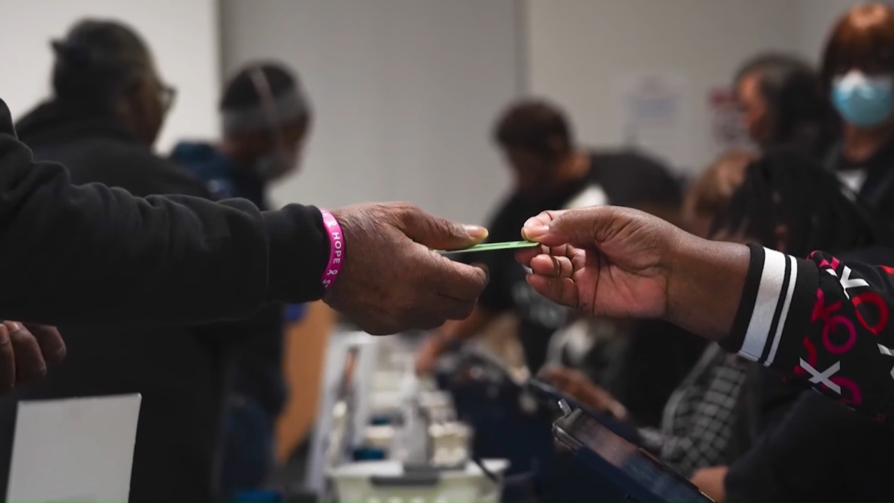 A person hands a green card to an applicant at an immigration office