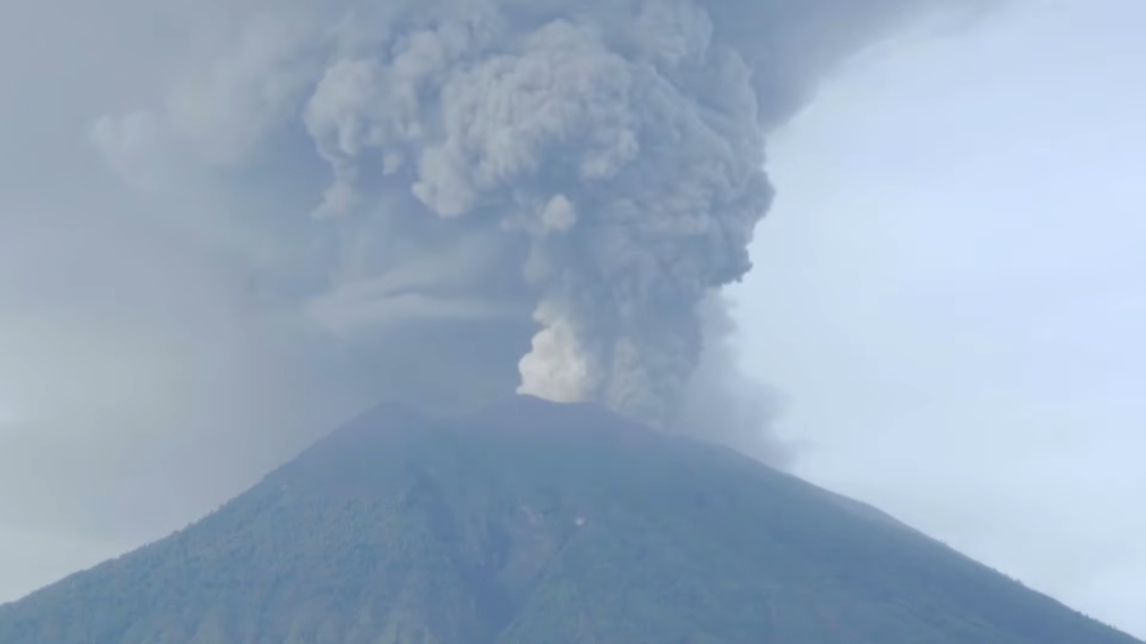 A thick ash cloud rises above a mountain after an eruption