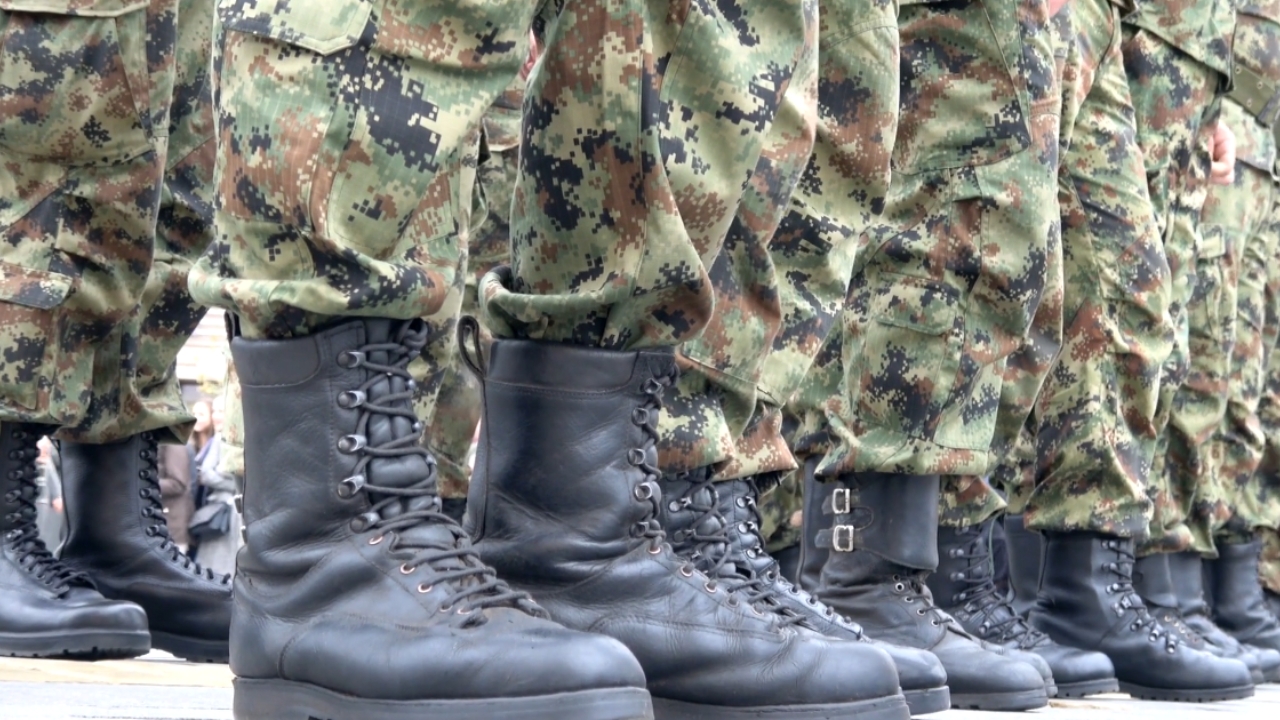US military personnel stand in formation in camouflage uniforms and black combat boots