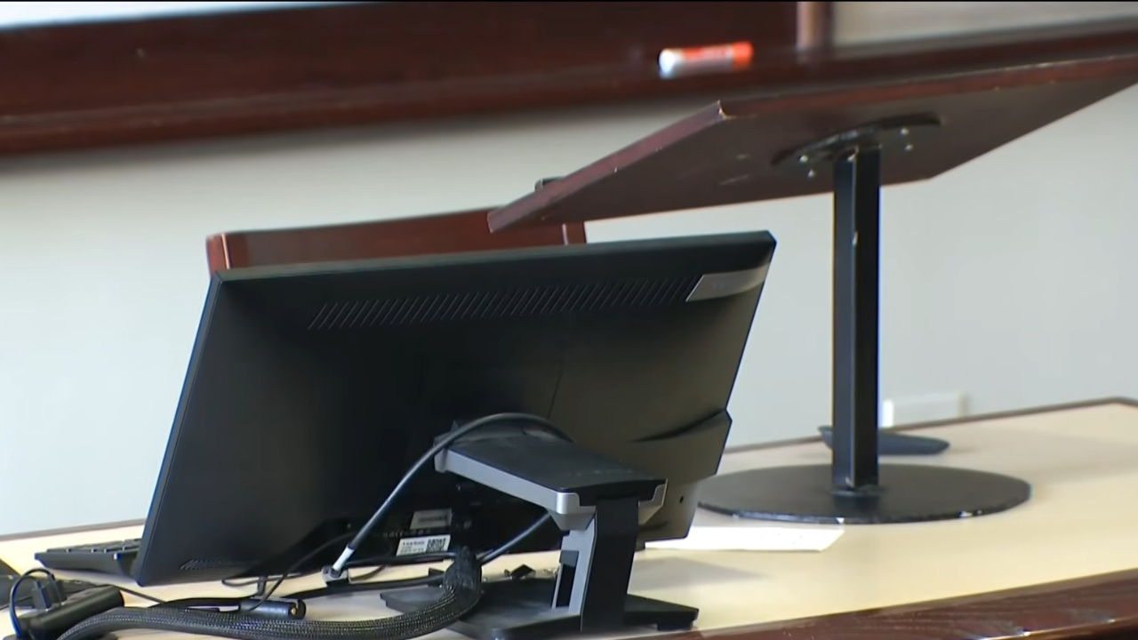 A classroom computer monitor sits beside a lectern