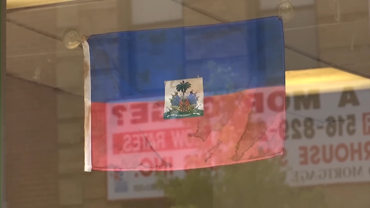 A Haitian flag hangs in a window near posted signs