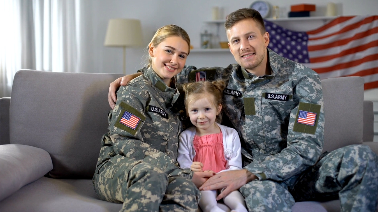 A U.S. military couple sits on a couch with their daughter