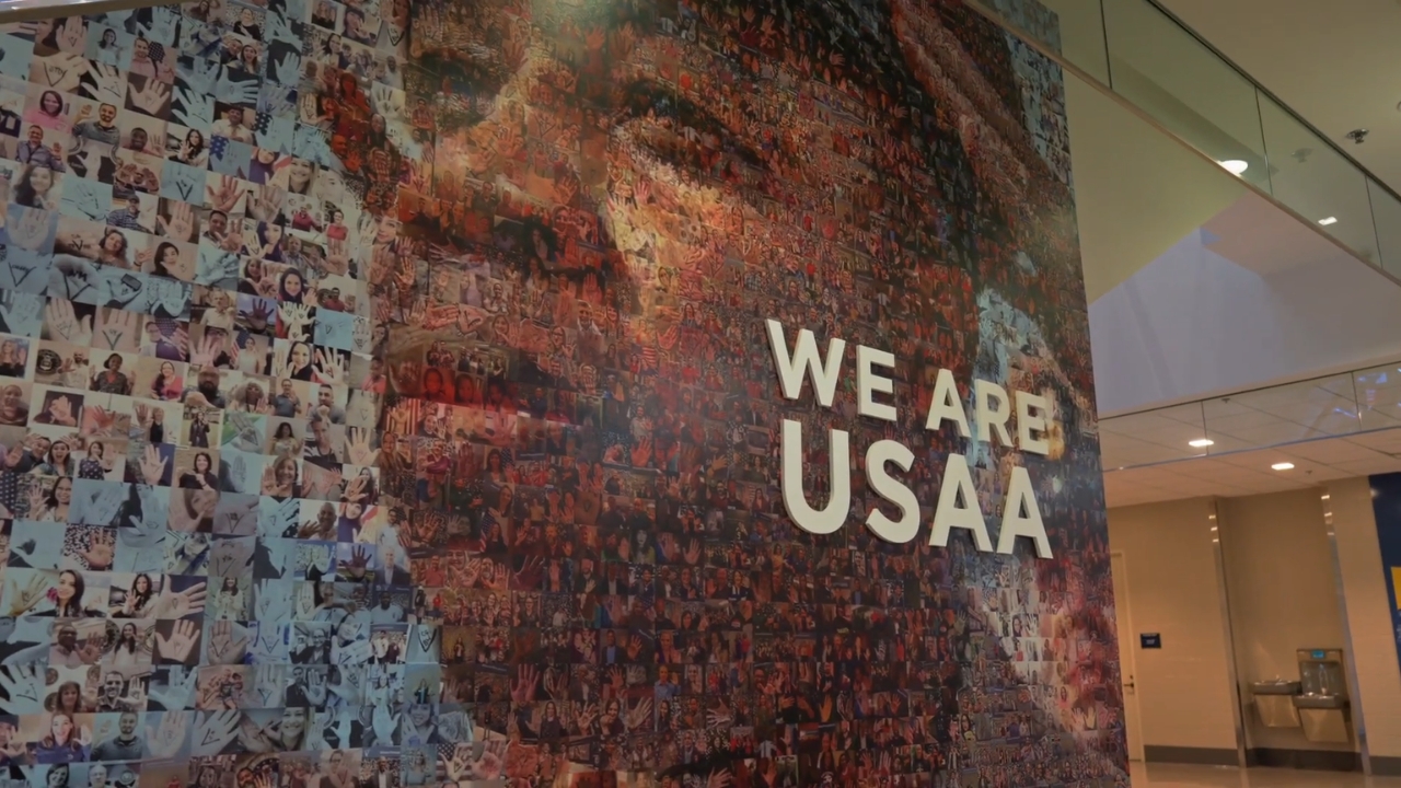 A USAA office wall features a large employee photo collage and the words “We Are USAA”