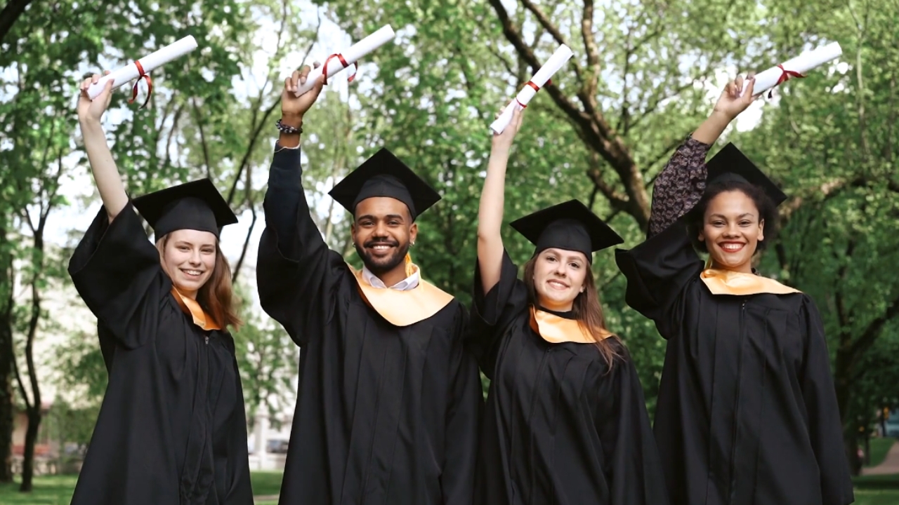 Graduates in caps and gowns celebrate Bachelor’s Degrees outdoors