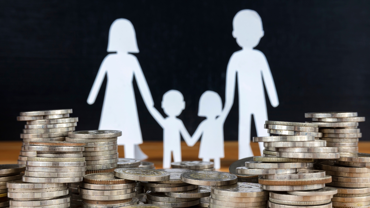 Paper family cutouts sit between stacks of coins