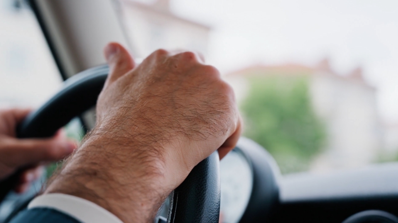 Driver grips a steering wheel inside a car