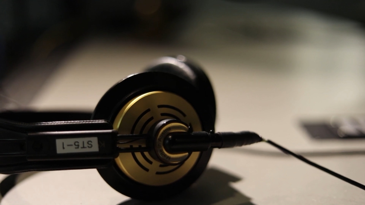 Black studio headphones lie on a desk beside audio equipment