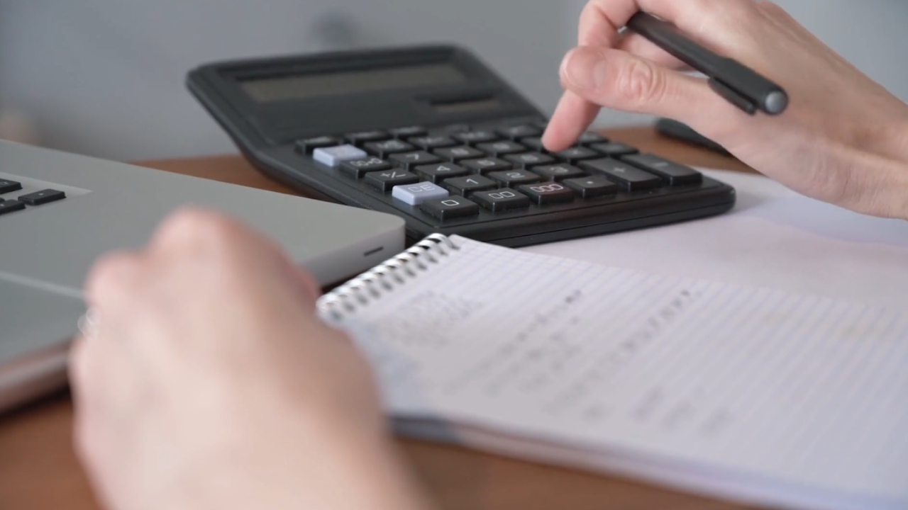 A person checks relocation costs with a calculator and notebook