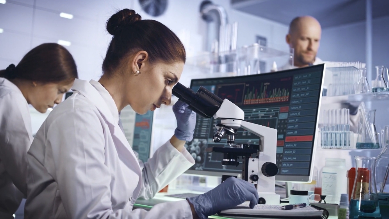 A scientist examines a sample under a microscope in a laboratory