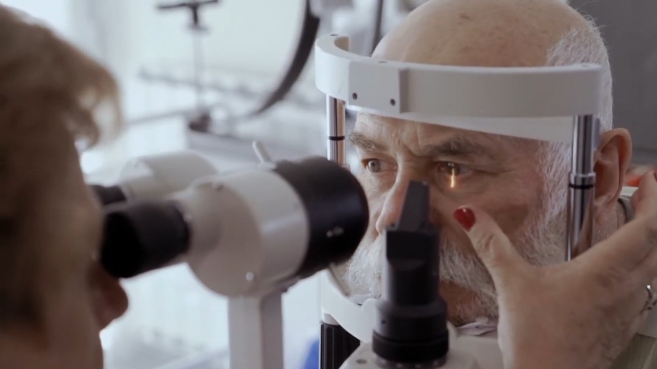 An older man has his eyes examined with ophthalmic equipment at an eye clinic