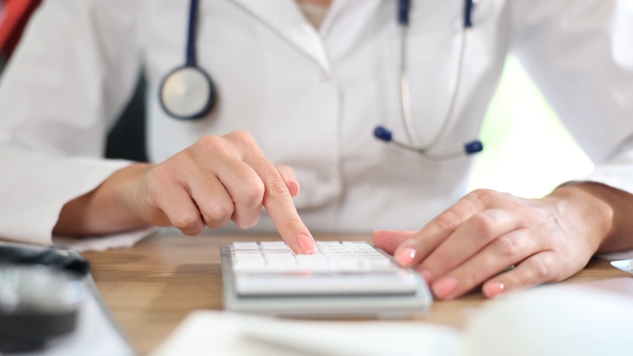 Doctor calculates medical costs at a desk