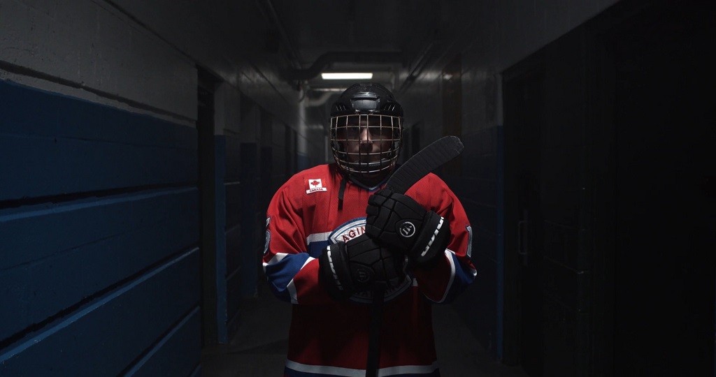 Hockey player holding a stick in an arena hallway