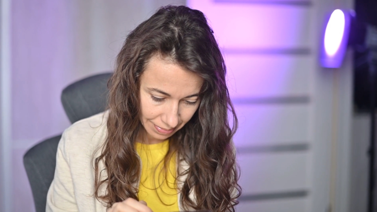Woman sits with her head bent forward as she uses a smartphone
