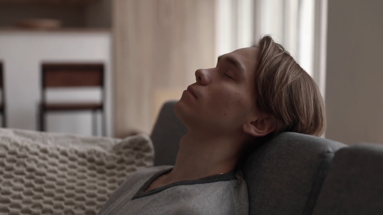 Woman relaxes on a couch with her eyes closed
