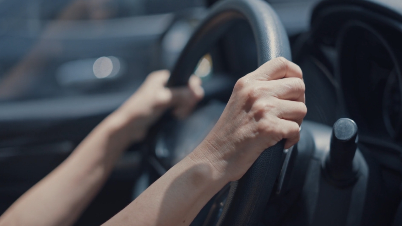 A driver holds the car wheel with both hands
