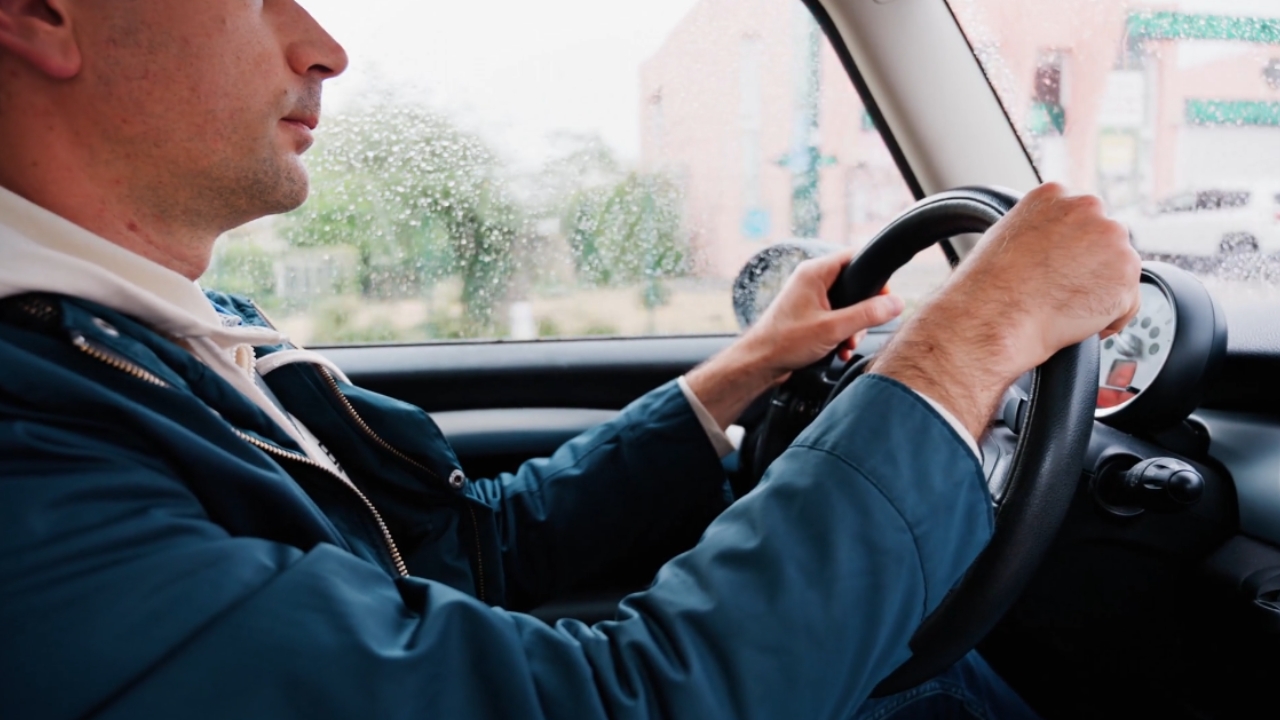 Driver keeps both hands on the wheel during rainy road conditions