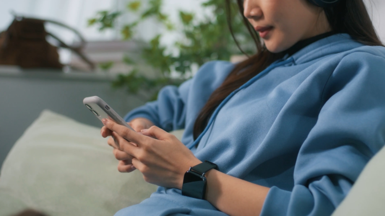Woman uses a smartphone while seated on a couch