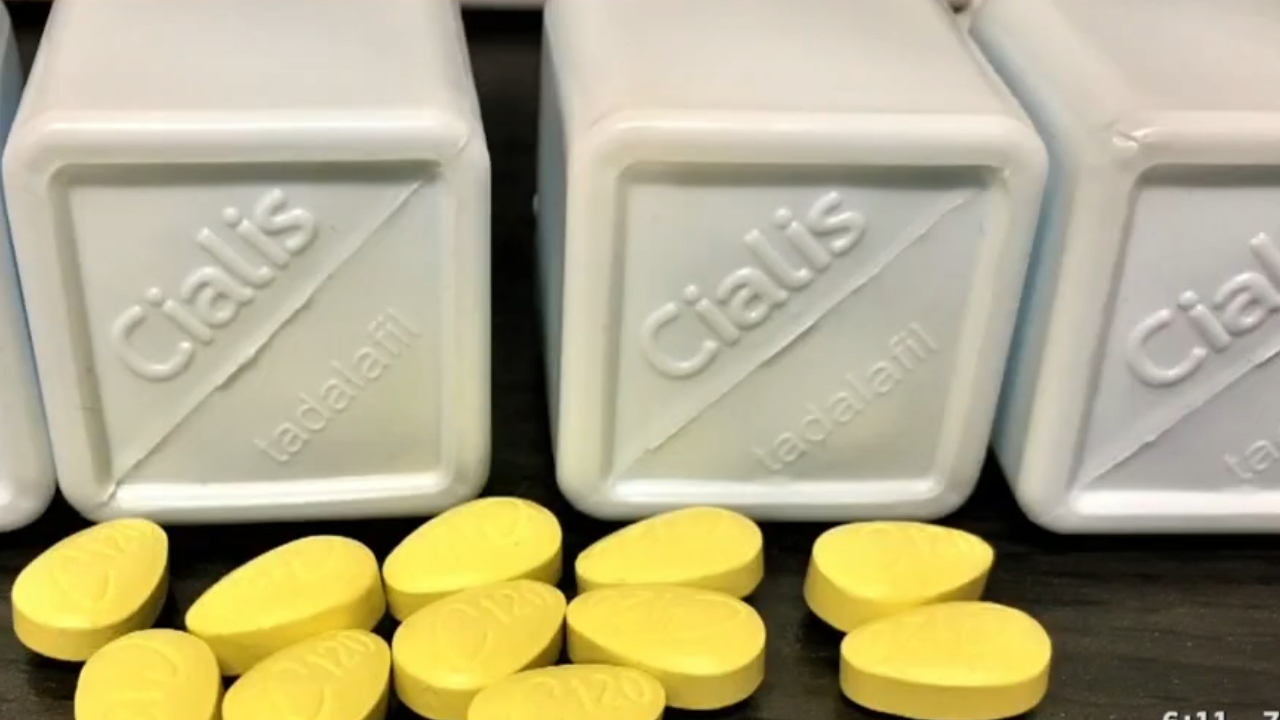 Yellow Cialis tablets sit in front of white tadalafil containers