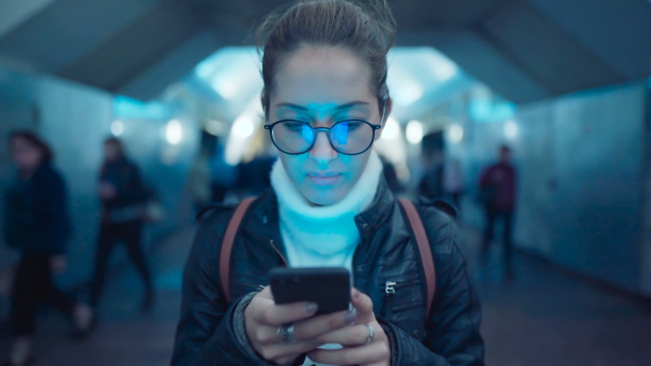 Woman looks down at her smartphone in a subway station