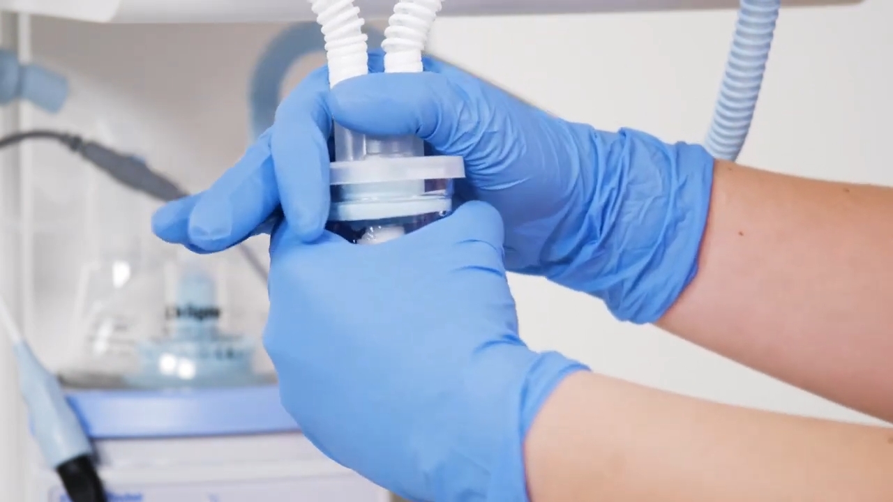 Gloved hospital worker checks a neonatal respiratory circuit connector.