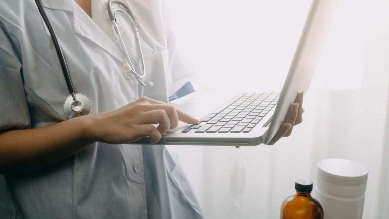 Doctor uses a laptop beside medication bottles during a telehealth consultation