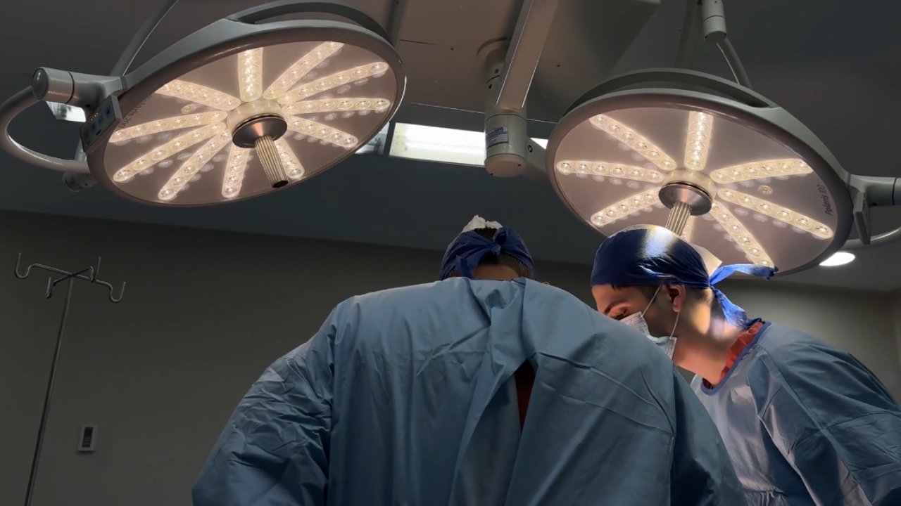 Surgeons perform an operation under surgical lights in a hospital operating room.