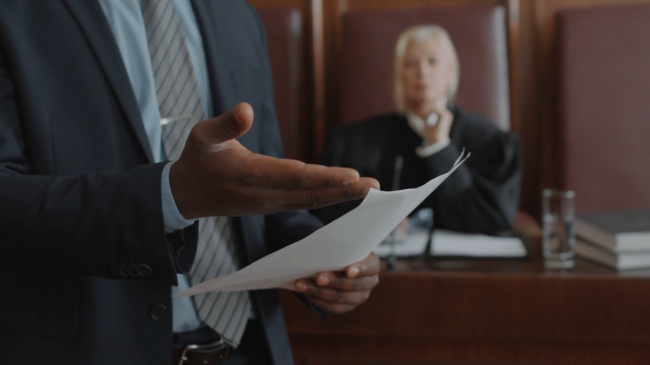A lawyer presents documents before a judge in a courtroom.