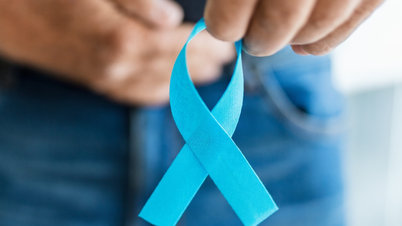 A man holds a blue ribbon for prostate cancer awareness.