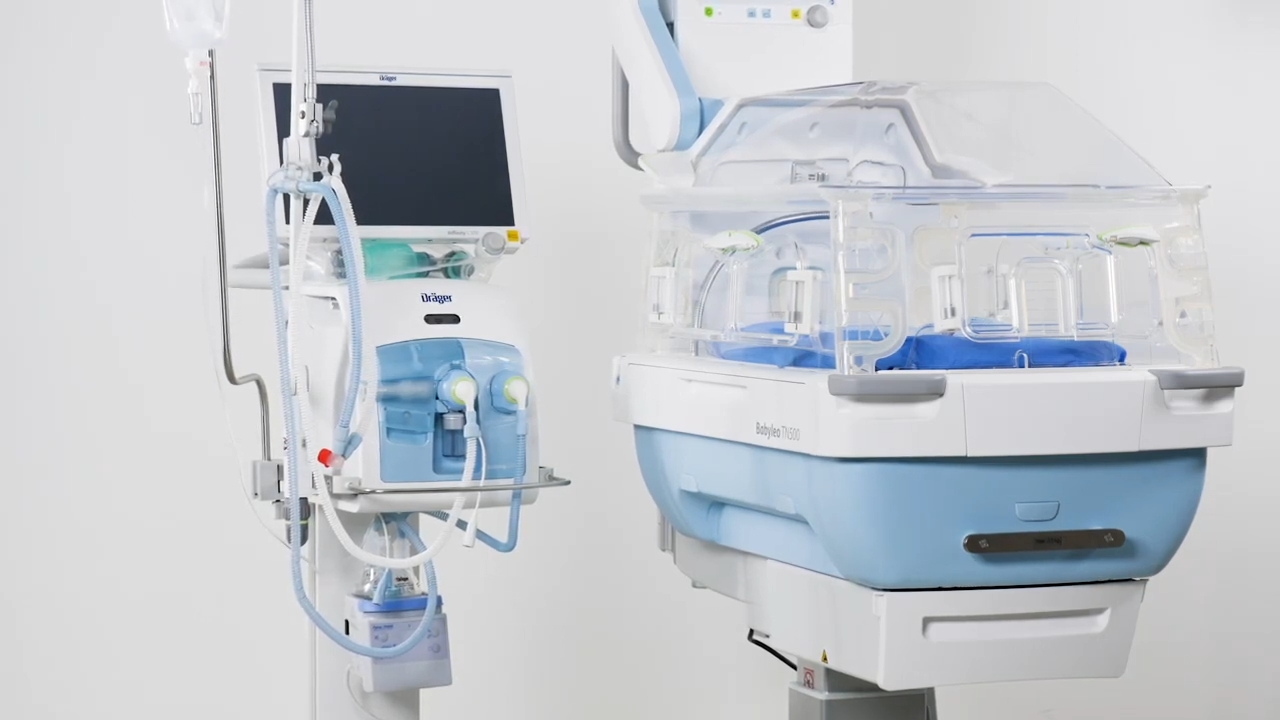 Neonatal incubator beside Dräger respiratory equipment in a hospital room.